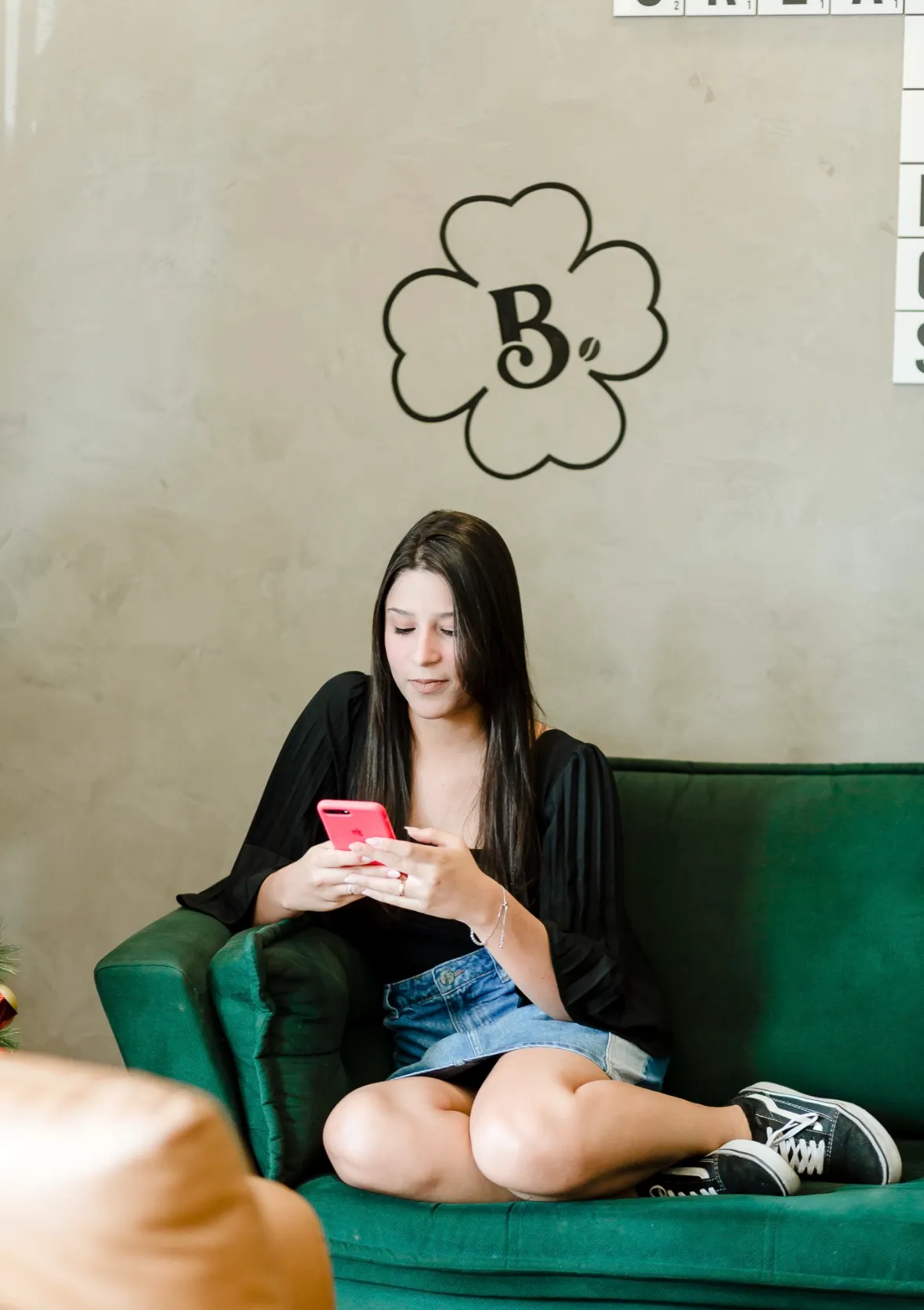 Amanda Polastro sentada no sofá utilizando o celular