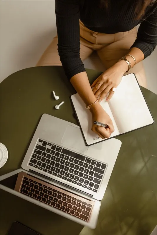 Mulher escrevendo em caderno em cima de mesa